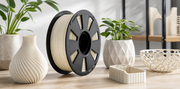 A PLA filament spool styled with modern printed home objects on a bright studio tabletop.